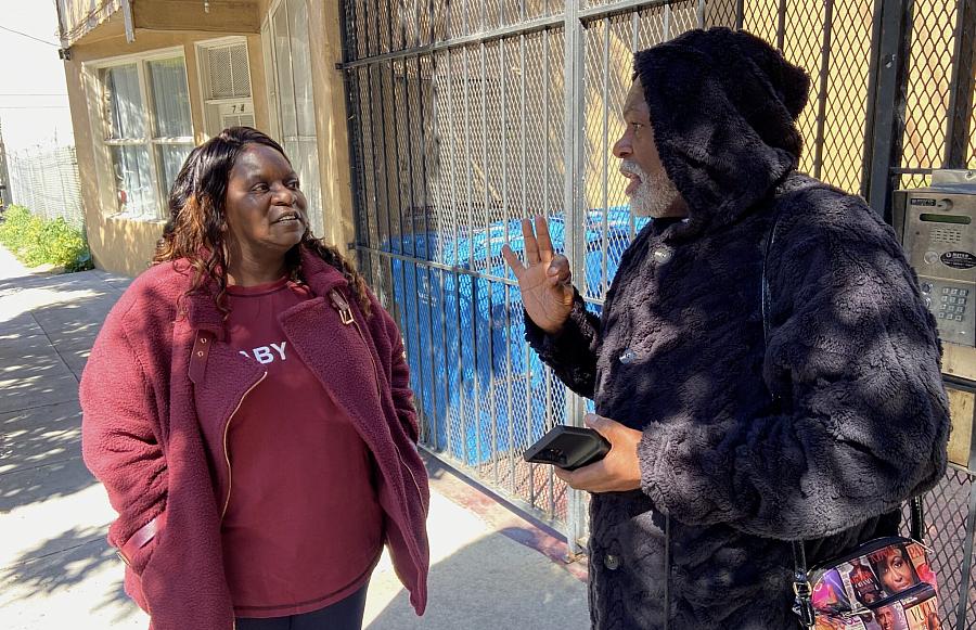 Two people talking, one wears a red top and another a black hoodie