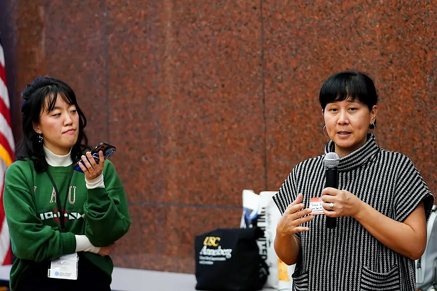 Person speaking into a mic as another watches