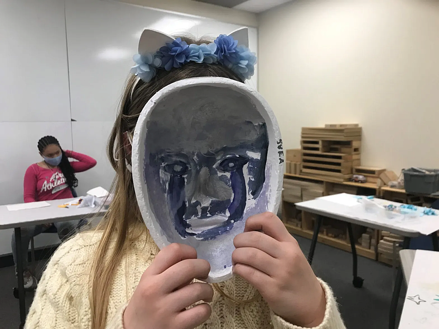 Child holding a painted mask