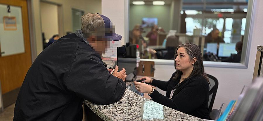A woman helps a man at the front desk of a clinic.
