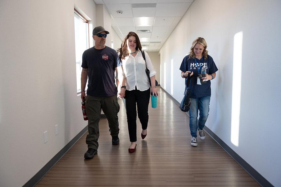 3 people walking through a hallway