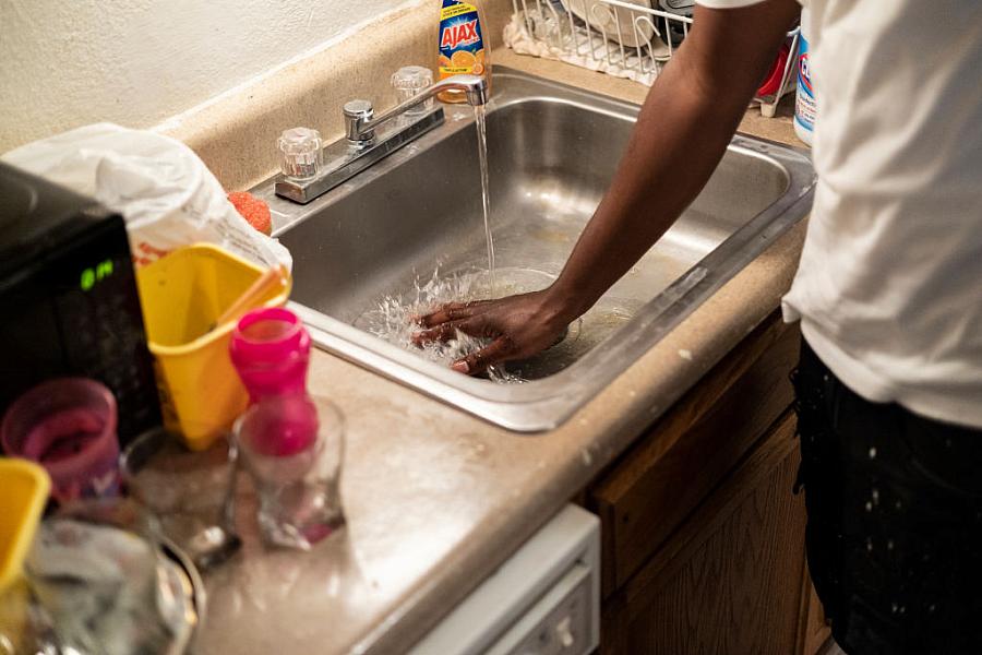 A man washes his hand in the sink.