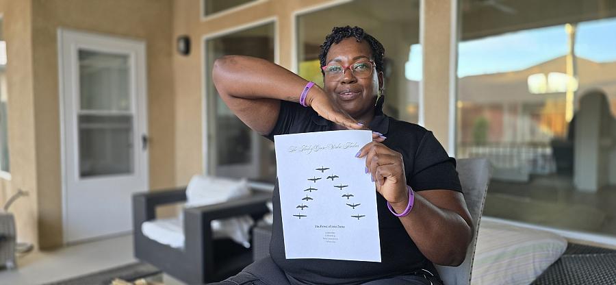A Black woman in glasses and a black t-shirt and cropped hair holds up a picture of geese to illustrate her training model.
