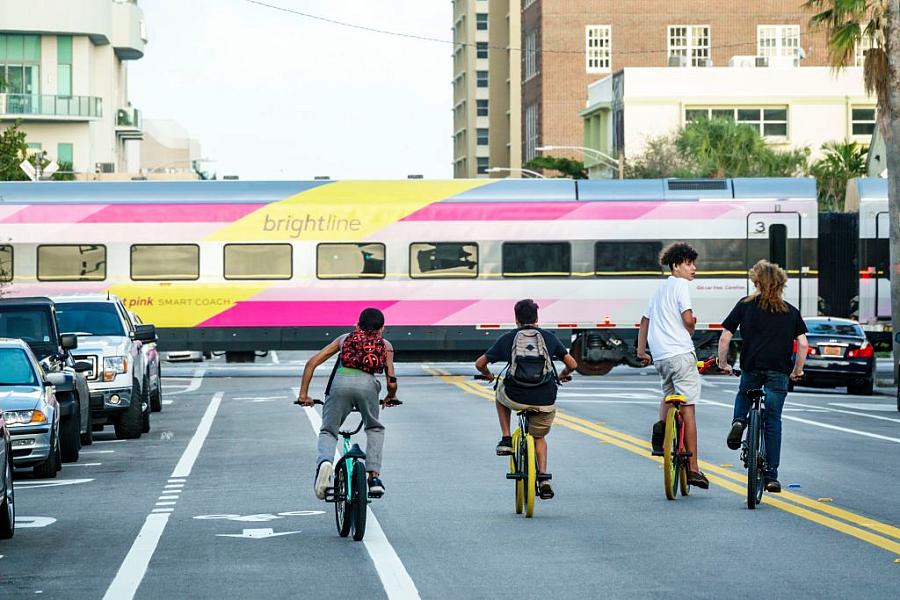 Teens ride bikes down a busy street.