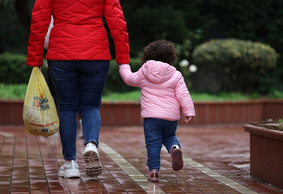 Adult walks hand-in-hand with small child