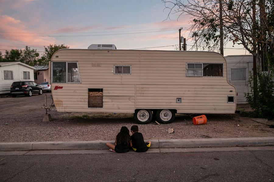 Two children sit on the side of a street.