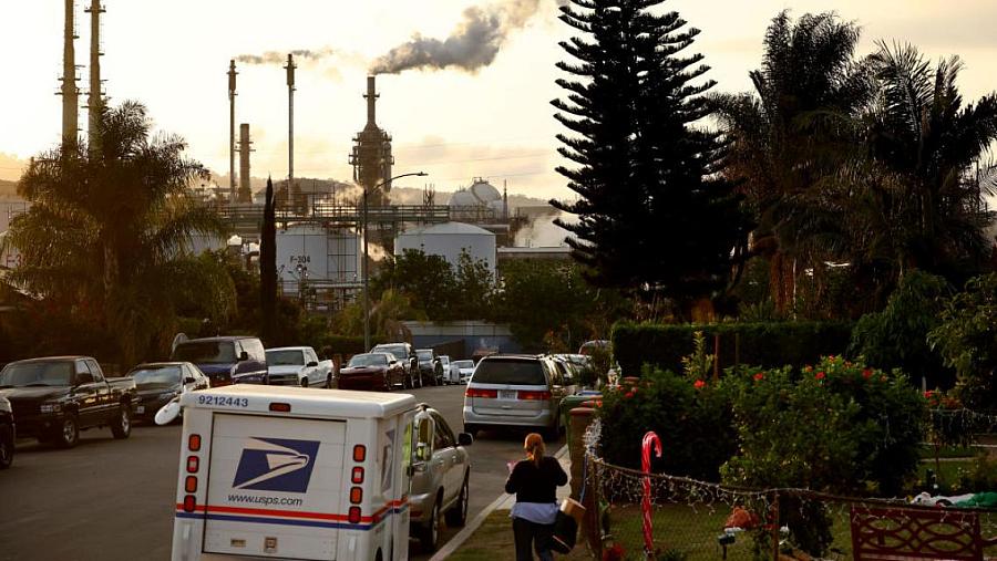 A mail carrier works in the shadow of the Phillips 66 refinery in Wilmington, California.