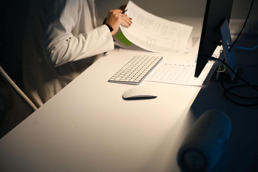 A researcher sits before a computer, looking at papers.