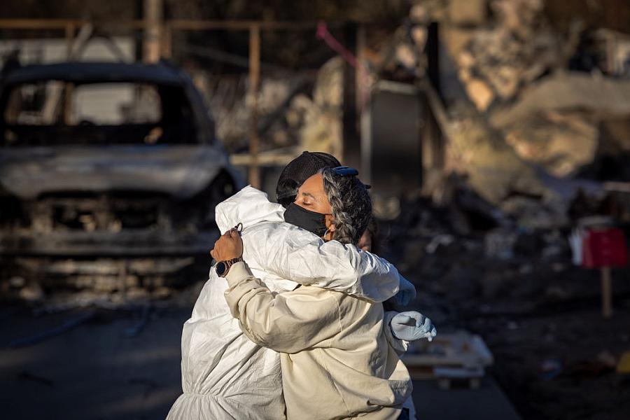 Two people embrace in the wake of the Altadena fires.