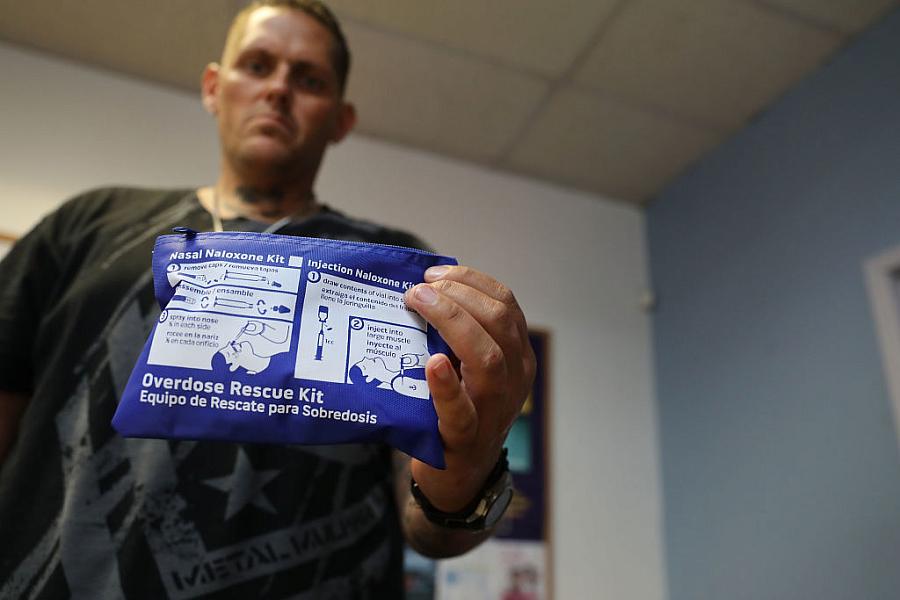 Image of an healthcare worker showing Nasal Naloxone kit in camera 