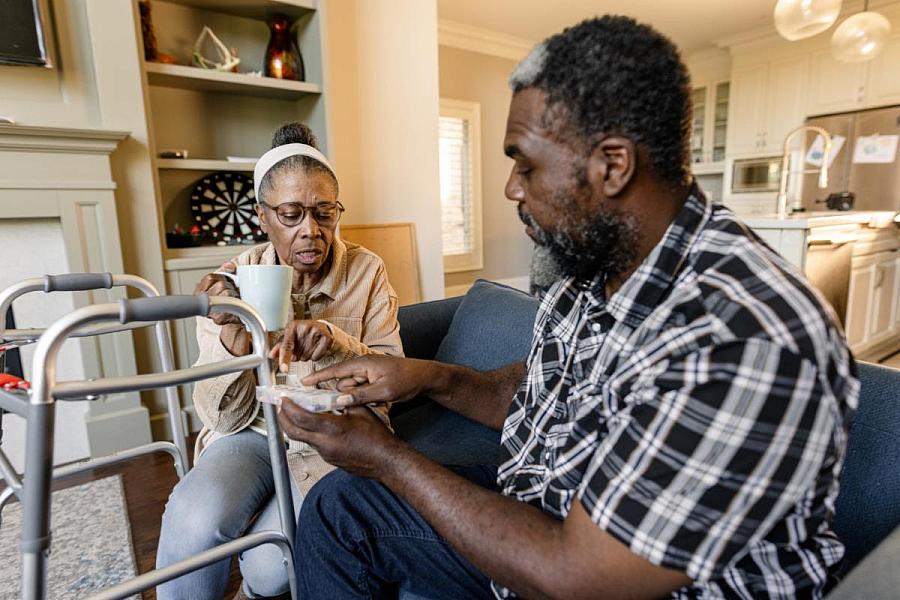 2 people discussing, one holding a medicine box