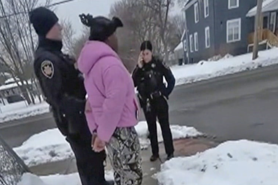 Child in pink jacket handcuffed with 2 people in uniform near them