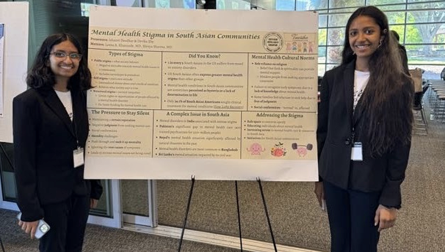 A young Desi woman presents a poster at a Mental Health Conference 