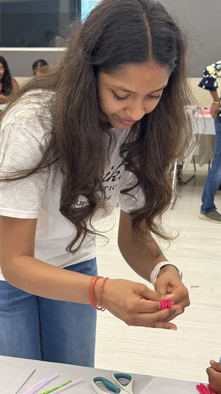 A young Desi woman helps with an art project at a white table