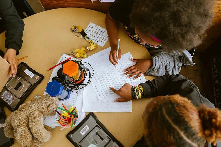 Children doing assignments on the table.