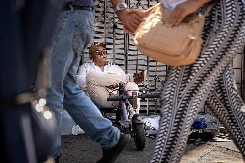 Image of a person sitting on street selling cookware.