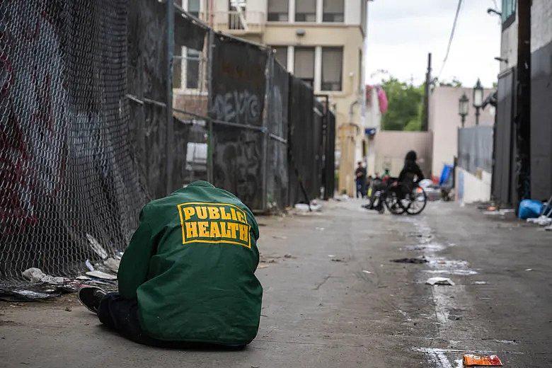 A person sleeping on the street while sitting