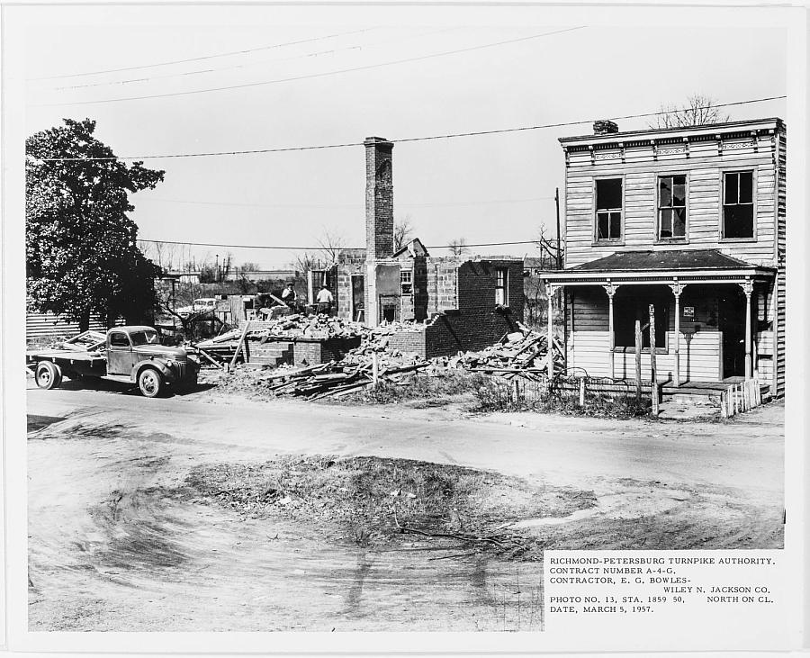 Black and white picture of a road with a car and building