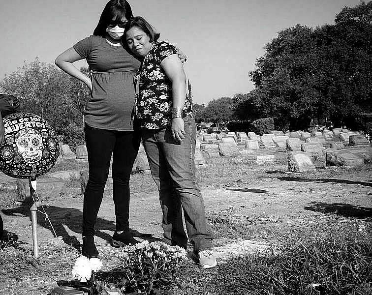 Two family members visit a grave in a cemetary.