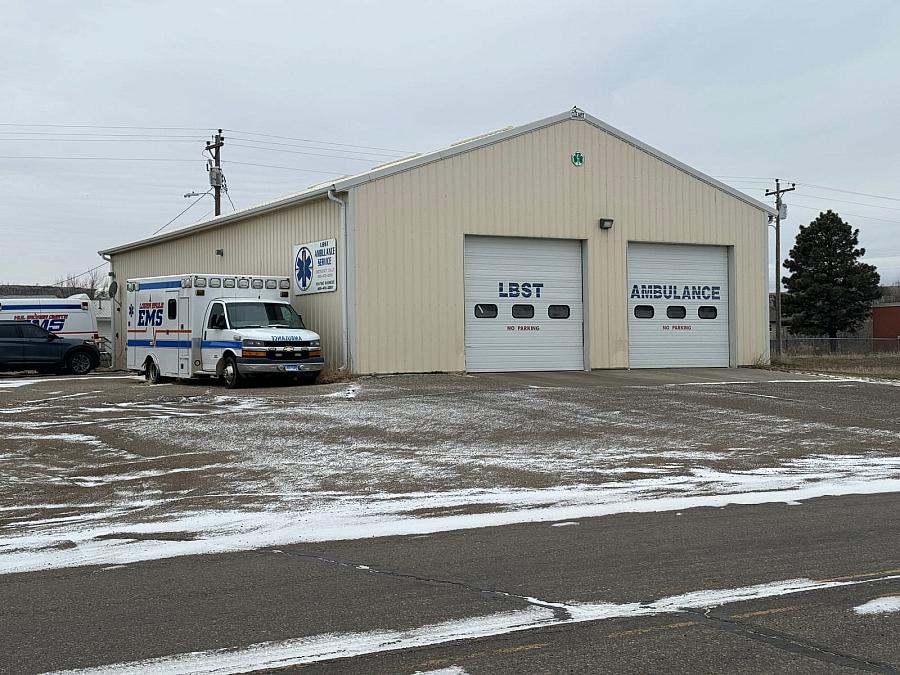 Ambulance parked by a warehouse looking structure