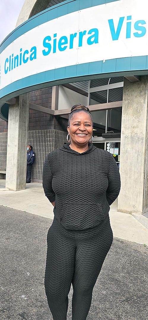 A young Black woman stands outside a clinic.