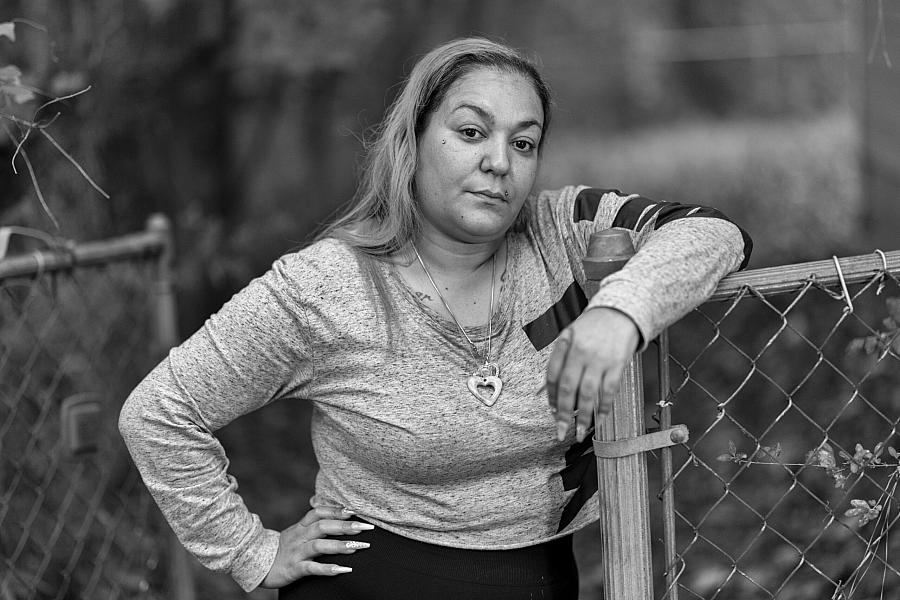 Black and white picture of a person leaning on a fence