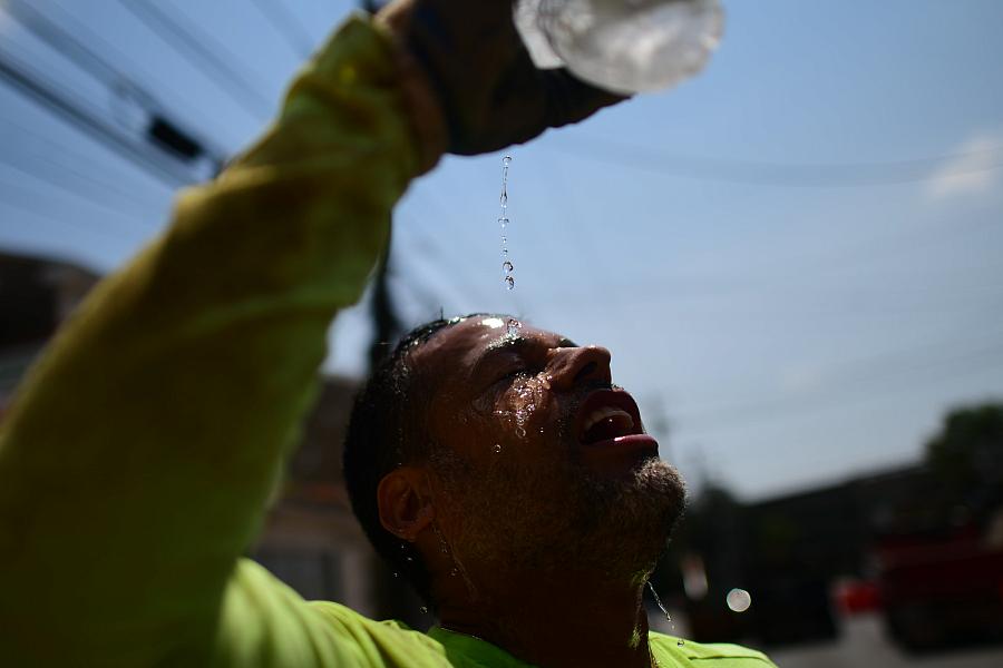 A man throwing water on his face for relief from the sun's heat.