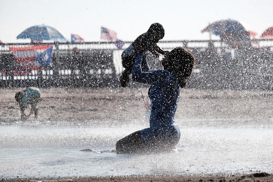 Image of a person playing with their child in the water at beach.