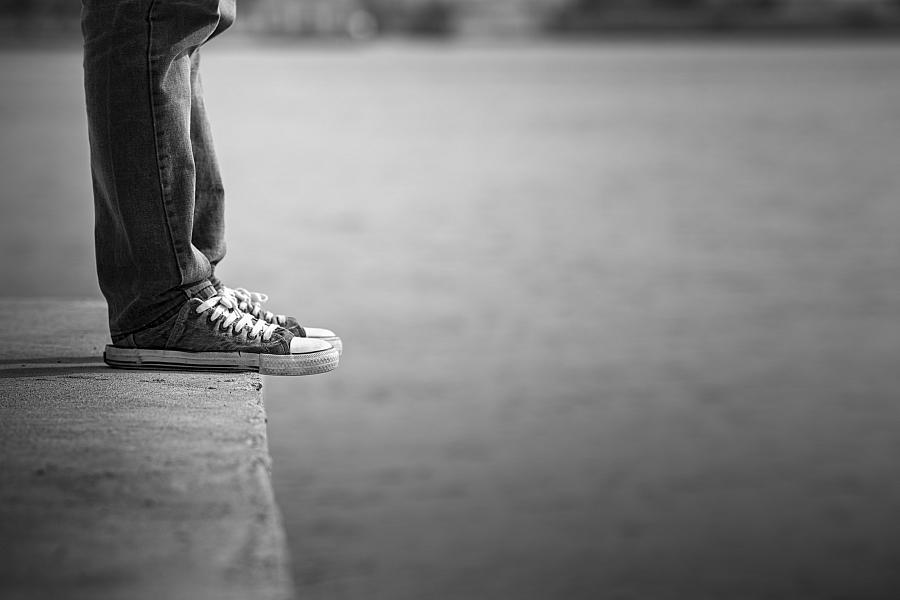 A black and white picture of legs with sneakers