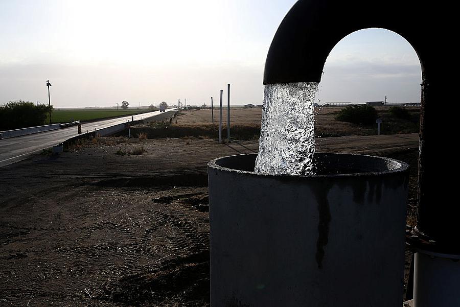A well pipe pouring water into a large metal tank
