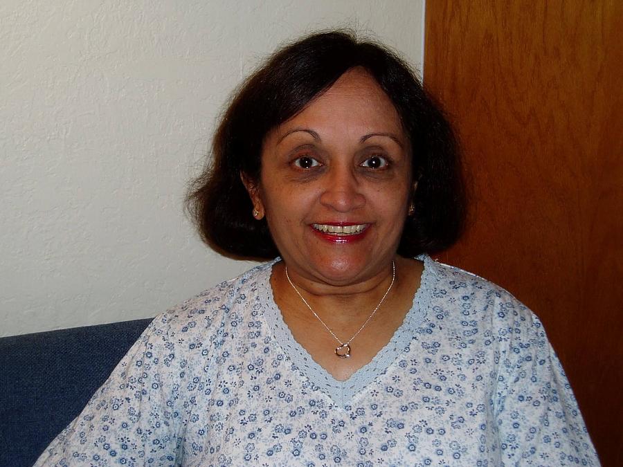 An older Indian woman with a dark bob smiles at the camera