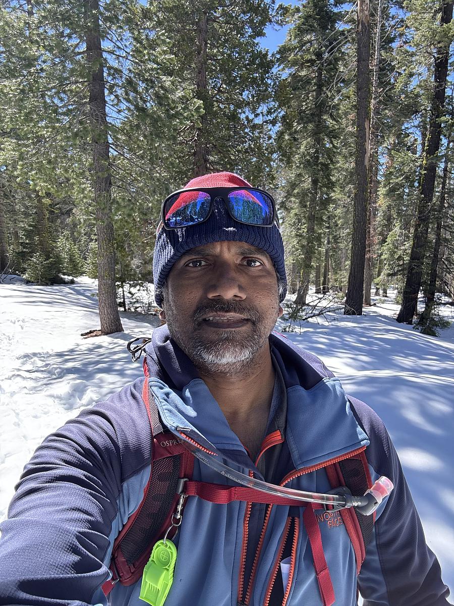 A Sri Lankan man stands in a snowy forest