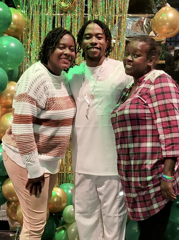 3 people standing together in front of balloons and tassels