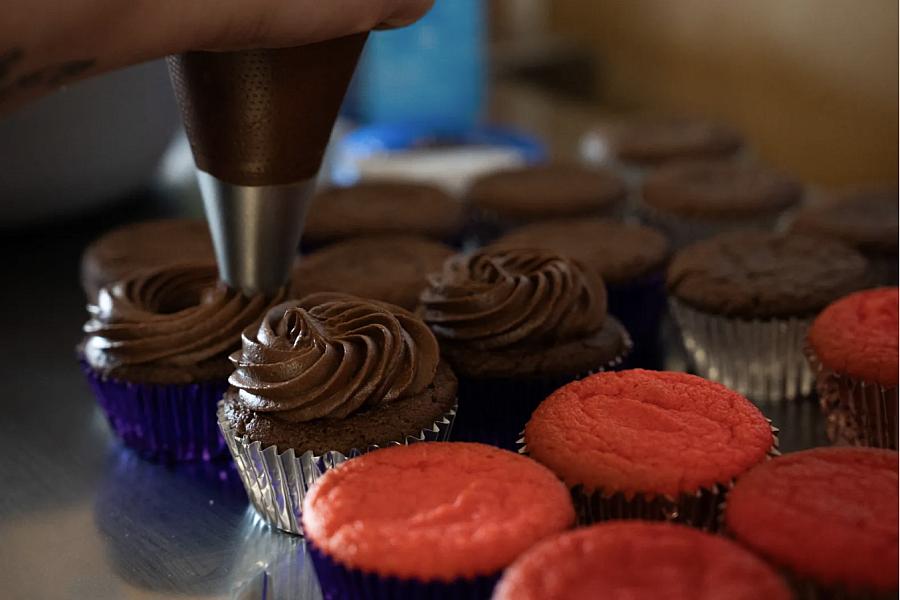 Icing being piped onto cupcakes