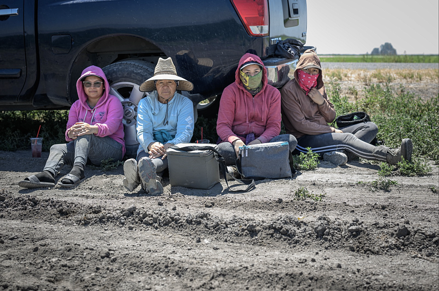 4 People sitting on the ground by a car