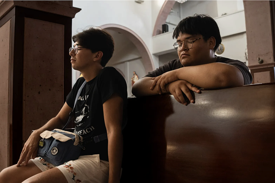 2 people seated on benches with their eyes closed