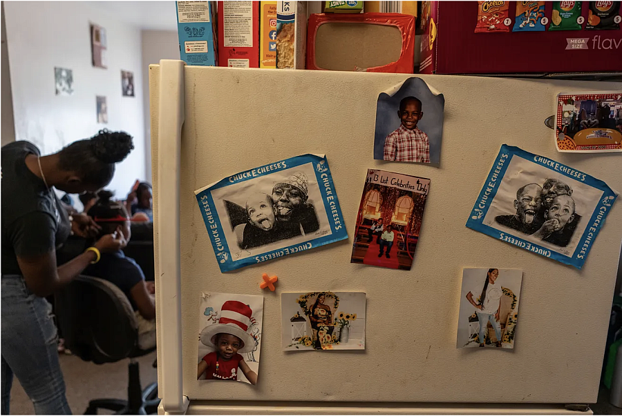 Refrigerator with pictures on it, a person doing a child's hair in the background