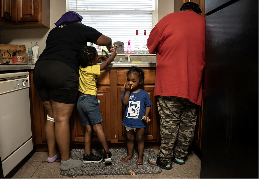 2 People and 2 children by a kitchen sink