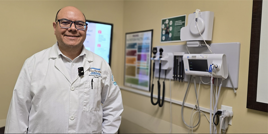 Dr. Hector Arreaza, a Venezuelan-born and educated doctor stands in his lab coat inside his office smiling