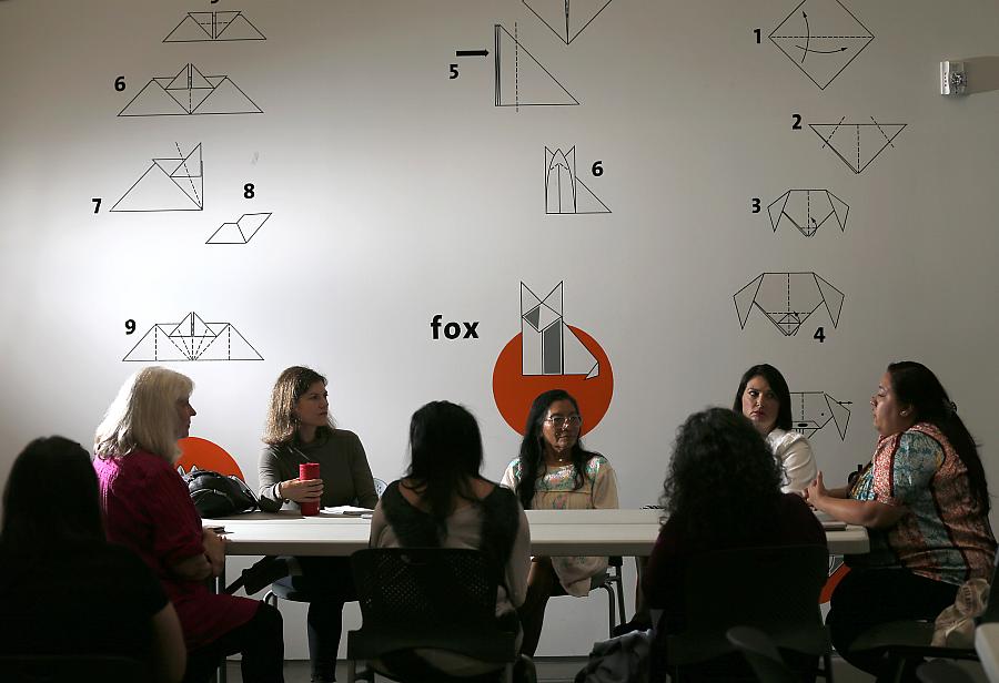 A meeting being held in a room with people seating across a table