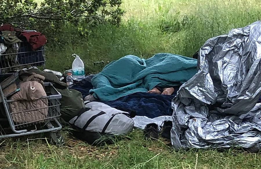 Person under a blanket near a tent