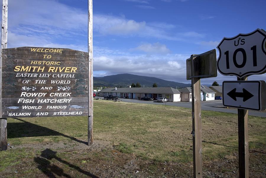 wooden "Smith River" sign next to some other signs