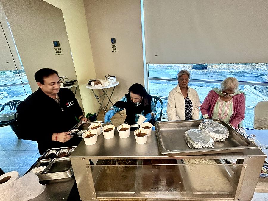 4 people behind a table with food containers on it