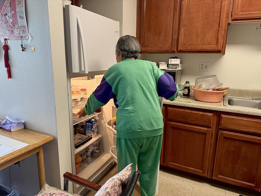 a woman opening her refrigerator
