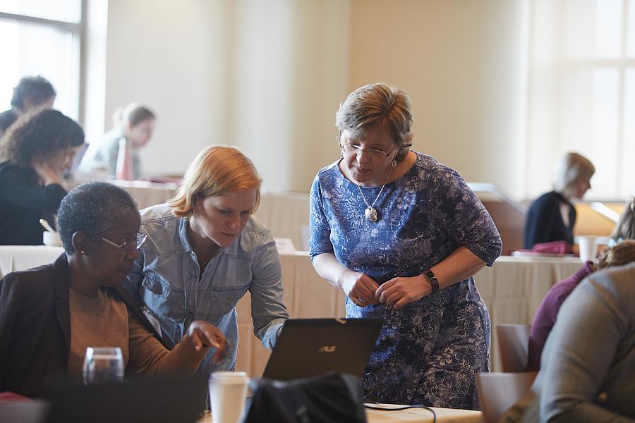 Fellows and mentors confer before a laptop.