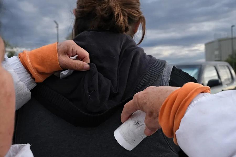 Image of person's hand checking other person's hoodie
