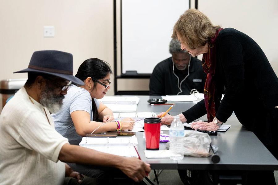 A reading instructor helps a woman decode a series of words during an adult literacy class in Bellaire