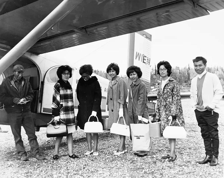 A group of people stand by a small plane
