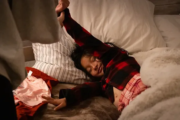 Child stretching in bed in pajamas