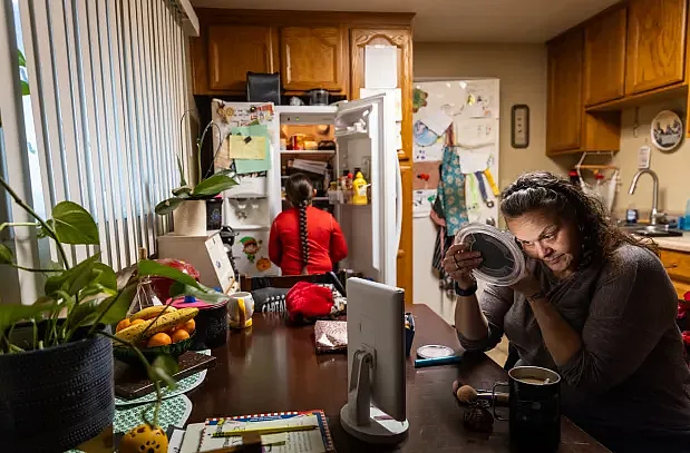 Woman applying makeup at kitchen table